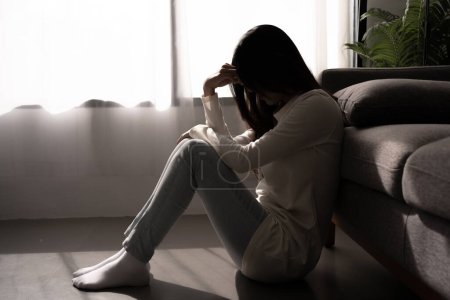 Foto de Young woman feeling depressed and stressed sitting in dark bedroom. Mental Health Concept. - Imagen libre de derechos