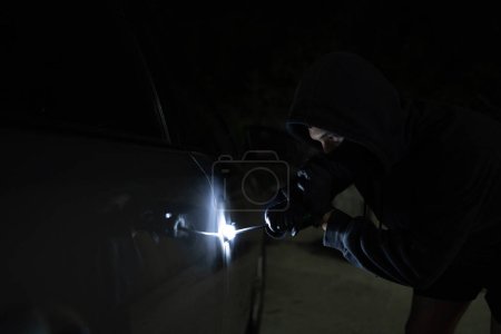 Photo for Man in black trying to steal a car. Car theft concept. - Royalty Free Image