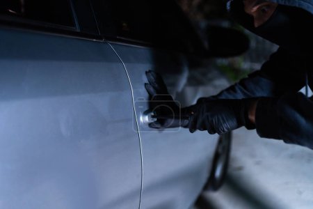 Car thief using a tool to break into a car