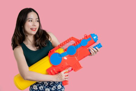Téléchargez les photos : Belle femme asiatique souriant et tenant un pistolet à eau en plastique pour le festival Songkran en Thaïlande. - en image libre de droit