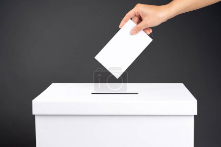 Wählerin hält Stimmzettel in der Hand über Stimmzettel für Stimmabgabe auf schwarzem Hintergrund.