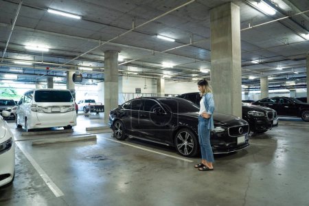 Photo for Lost car concept : Stressed woman holding car keys in her hands where her car was stolen leaving only empty space - Royalty Free Image
