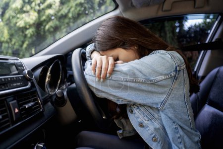 Asiatin gestresst oder müde im Auto liegend am Steuer