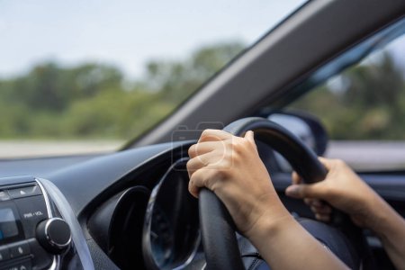 Female hands on the car steering wheel close up. Woman is driving a car.