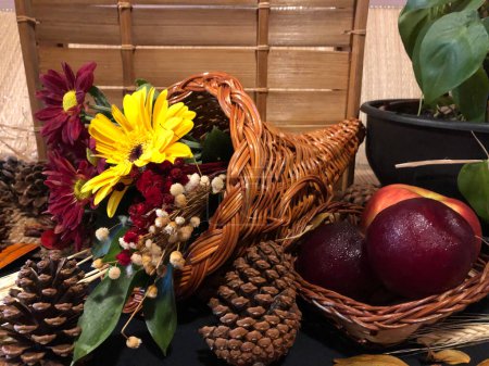 Foto de Cornucpia com flores coloridas sobre a mesa com vaso de plantas e cesta com mas. - Imagen libre de derechos