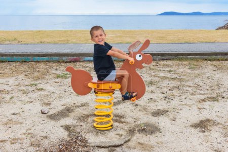 Téléchargez les photos : Un garçon monte un âne sur une aire de jeux pour enfants - en image libre de droit