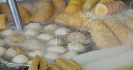 The Japanese food oden is being cooked in a pot on a small street vendor.