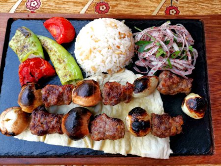 Téléchargez les photos : Meat skewers with rice on a black board background - en image libre de droit