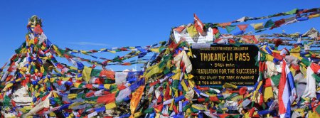Prayer flags and signboard on the Thorang La mountain pass, Nepal.