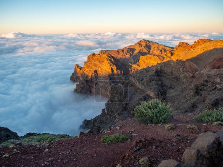 Téléchargez les photos : Montagnes rocheuses regardant des nuages dans le soleil du matin sur l'île de La Palma, Espagne. Caldera sous les nuages d'inversion. Lever de soleil avec des pics rocheux - en image libre de droit