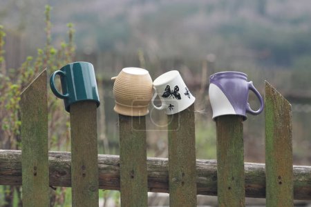 Téléchargez les photos : Vieilles tasses colorées accrochées à une clôture de pays - en image libre de droit
