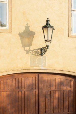 Téléchargez les photos : Lampe historique avec une ombre sur un mur de couleur ocre - en image libre de droit