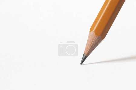 Téléchargez les photos : La pointe d'un crayon en bois projetant une ombre sur du papier blanc. Arrière-groupe blanc - en image libre de droit