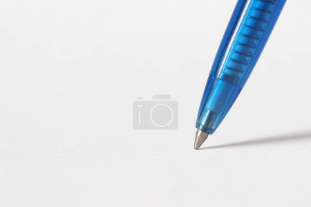 Téléchargez les photos : La plume d'un stylo à bille bleu jetant une ombre sur du papier blanc - en image libre de droit
