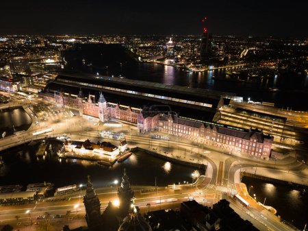 Amsterdam city center skyline by night aerial drone overhead view. Amsterdam Centraal, Ij, Prins Hendrikkade, public transport, traffic at night. Bright lights urban