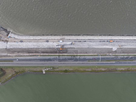 Foto de El sistema de defensa contra inundaciones Afsluitdijk en los Países Bajos entre Holanda Septentrional y Frisia cerrando el IJsselmeer frente al Mar de Wadden. Presa e infraestructura vial vista aérea del dron. - Imagen libre de derechos