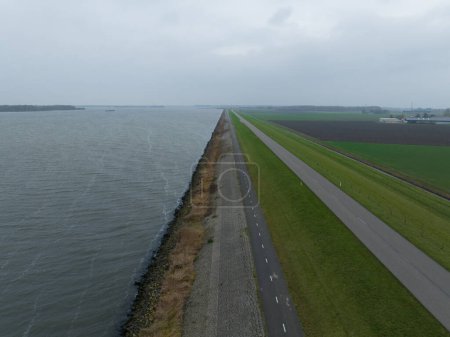 Photo for Dyke road infrastructure in The Netherlands, Holland. Flood barrier along the Ijselmeer near Lelystad and Urk. Water and land coast line. - Royalty Free Image