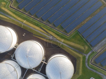 Photo for Witness the contrast between the old and new ways of energy production through a birds eye view of oil storage tanks and solar panels coexisting in a single location.. - Royalty Free Image