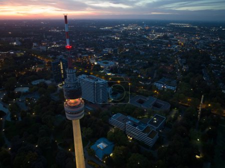 Foto de Vista aérea del dron de Florian Tower Florianturm en Dortmund, Alemania por la noche, con el horizonte de la ciudad en el fondo. - Imagen libre de derechos