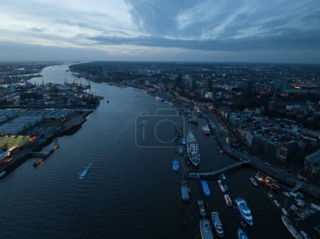 Skyline of Hamburg at dusk, the River Elbe and the large commercial industrial port. City view. Aerial drone view