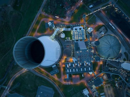 Aerial drone view on the Duisburg Walsum power station at night. A coal fired thermal power station, also creates heat for district heating and a 300m high chimney. Energy infrastructure in Germany