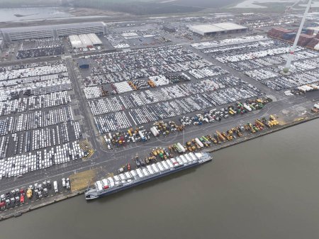 Aerial drone views of transportation of vehicles over seas from a sea port terminal, specifically the Zeebrugge, intermodal logistics, roll on roll off cargo, and loading unloading of new vehicles.