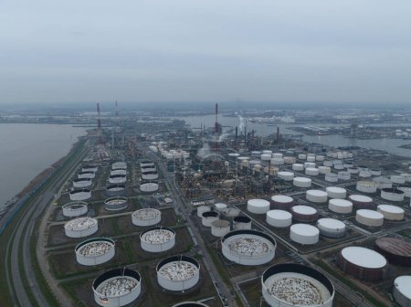 Aerial drone view on refinery in the port of Antwerp. Processing of fossil fuels. Petroleum industry at dusk. Heavy industrial installation. Silos containers and smokestacks. Antwerp, Belgium.