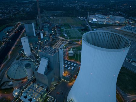 Drohnenaufnahme des nächtlichen Kraftwerks Duisburg Walsum, einem Kohlekraftwerk mit 300 m hohem Schornstein, und der Energieinfrastruktur in Deutschland in der Nähe des Kühlturms. Symbolträchtig