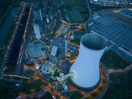 Aerial drone view of the Duisburg Walsum power station at night, a coal-fired thermal power station with a 300m high chimney, and energy infrastructure in Germany, close to the cooling tower. Iconic
