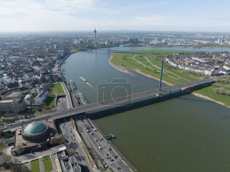 Aerial drone view over Dusseldorf, including the Rhine River and the Oberkasseler Brucke, capturing their scenic and architectural features.
