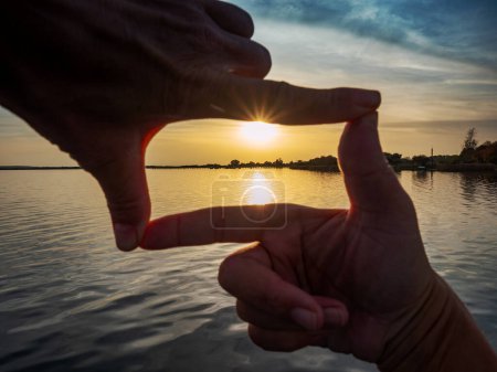 Foto de Marco del dedo de la composición. Chica manos captura en marco puesta de sol por encima del lago silencioso. - Imagen libre de derechos