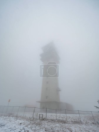 Foto de Torre de radiocomunicación de 80m de altura en la niebla pesada. El pico de la montaña Klinovec de 1244m de altura. Las montañas mineras, noreste de la República Checa RFepublic - Imagen libre de derechos