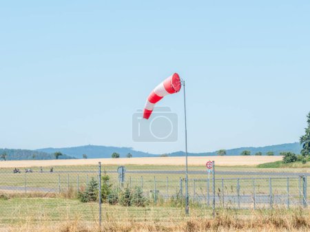 Photo for Summer hot day on sport airport with abandoned windsock, wind is blowing and windsock is moving - Royalty Free Image