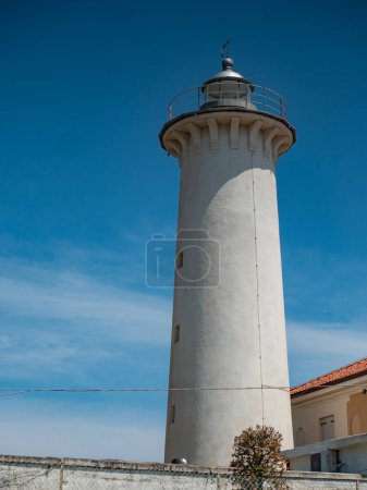Foto de 2023 25 de julio, Faro di Punta Tagliamento, Bibione, Italia. Faro blanco popular con una torre de hormigón y una luz activa junto a una playa tranquila, construido en 1913. - Imagen libre de derechos