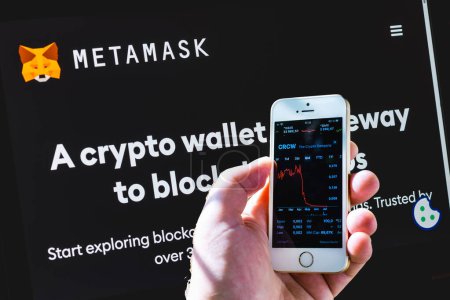 Photo for Hand holding mobile phone MetaMask app running at smartphone screen with trading candlestick chart at screen background. MetaMask is software crypto wallet.Telsiai,Lithuania.07-25-2023. - Royalty Free Image