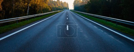 Photo for Empty road in the middle of the autumn forest. Beautiful trees,roadway,trees with green foliage and overcast sky.Landscape with empty asphalt road through woods in autumn.Travel concept.Banner. - Royalty Free Image
