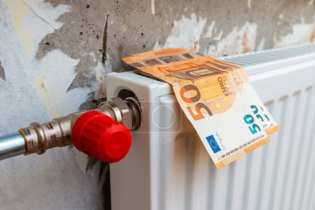 Expensive heating. Heat price growth. Heating radiator at home on it euro current money.