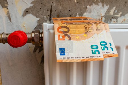 Expensive heating. Heat price growth. Heating radiator at home on it euro current money.