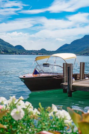 Photo for Splendid view of Lake Lugano with the luxury speedboat moored at the shore in the village of Morcote in Switzerland. Beautiful Swiss landscape of the lake and Alps in the background on a sunny summer day. - Royalty Free Image