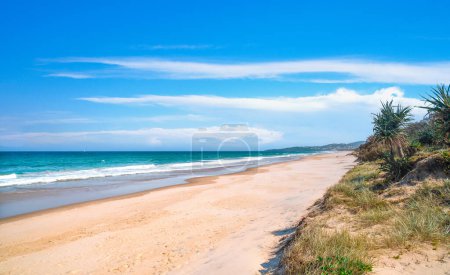 Schöne Aussicht auf einen unberührten Strand und Meereswellen, die an einem sonnigen Tag an der Küste krachen. Tropischer Strand Hintergrund.