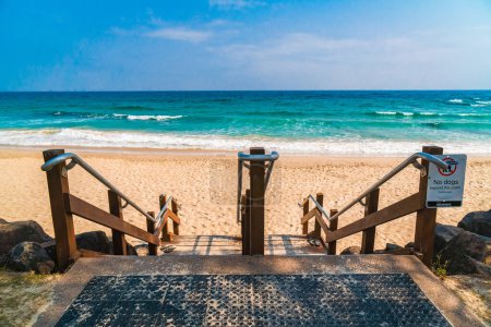 Foto de Escaleras de madera a la playa con olas de mar aplastantes en el fondo. Vista panorámica de Rainbow Bay Beach, una de las playas más populares de Gold Coast, Queensland, Australia. - Imagen libre de derechos