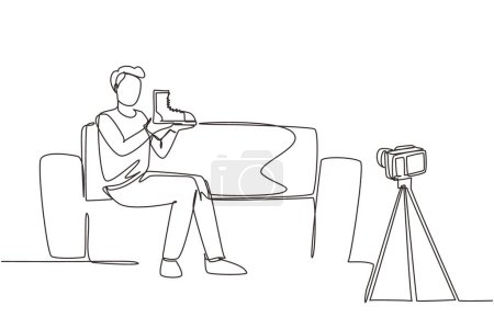 Illustration for Single one line drawing social media influencer reviewing boots. Smiling young man vlogging about men's sports shoe and filming himself at home on a video camera. Continuous line draw design vector - Royalty Free Image