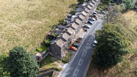 Foto de Aerial drone photo of the beautiful village of East Morton in Keighley in Yorkshire in the UK, showing old historic rows of traditional terraced houses by a road surrounded by farmers fields. - Imagen libre de derechos