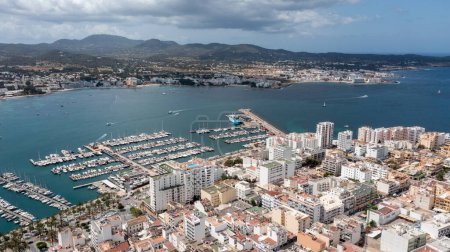 Téléchargez les photos : Photo de drone aérien d'une plage dans la ville de Sant Antoni de Portmany sur l'île d'Ibiza dans les îles Baléares Espagne montrant le port de plaisance et le port avec des hôtels et des appartements - en image libre de droit