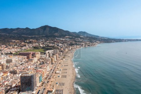 Téléchargez les photos : Photo de drone aérien de la belle plage devant la ville côtière de Fuengirola à Malaga Espagne Costa Del Sol, montrant la plage de sable, les hôtels et les appartements avec les montagnes en arrière-plan - en image libre de droit