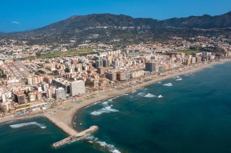 Téléchargez les photos : Photo de drone aérien de la belle plage devant la ville côtière de Fuengirola à Malaga Espagne Costa Del Sol, montrant la plage de sable, les hôtels et les appartements avec les montagnes en arrière-plan - en image libre de droit