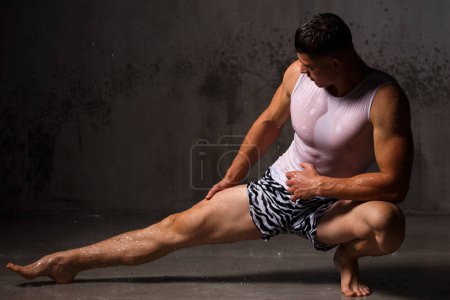 Photo for Bodybuilder flaunts his muscles and figure in the studio in the rain. - Royalty Free Image