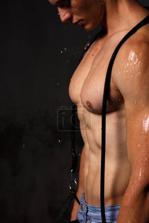 Foto de Culturista hace alarde de sus músculos y figura en el estudio bajo la lluvia. - Imagen libre de derechos