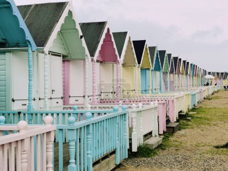 Téléchargez les photos : 8 avril 2023 - Suffolk, Royaume-Uni : Rangée de cabanes de plage de couleur pastel. Photo de haute qualité - en image libre de droit