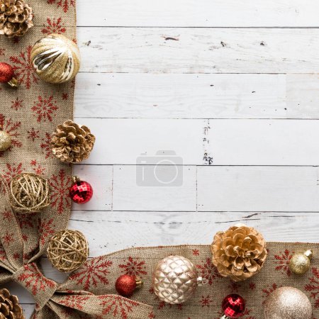 Holiday decorated border with ornaments and gold pinecones, in a square crop with copy space in the middle.